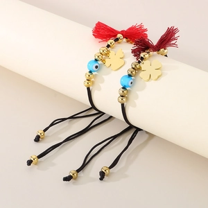 Detail of bohemian evil eye woven bracelets with golden clover charms and red tassels