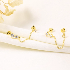Detail of s925 silver gold eye stud earrings with cubic zirconia and chain tassel