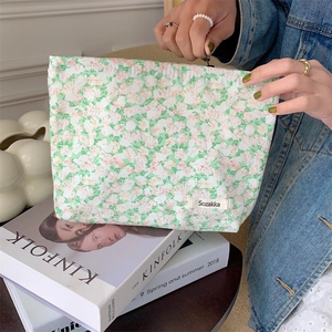Detailed texture of green floral cotton makeup bag with high-quality zipper and tag