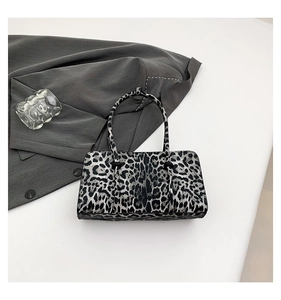 Detail shot of leopard print handbag with silver texture on grey suit background