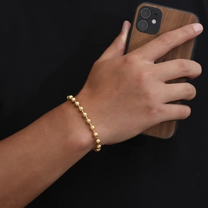 Close-up of golden beaded stainless steel bracelet worn on wrist for hip hop fashion