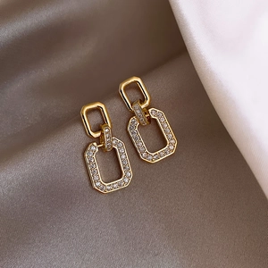 Elegant gold geometric chain earrings with sparkling zircons on soft silk background