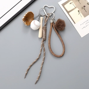 Close-up of baseball keychain with leather glove, wooden bat, and brown pompom charm