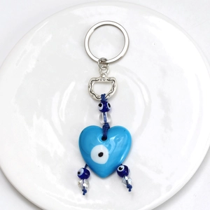 Macro detail of heart-shaped evil eye keychain with blue beads and silver metal clasp