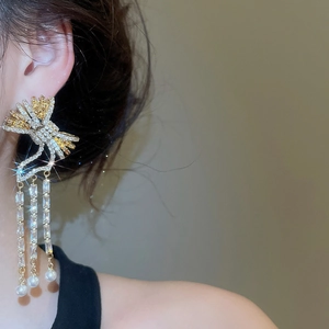 Detail of silver needle bow earrings with zircon tassels and pearls on model