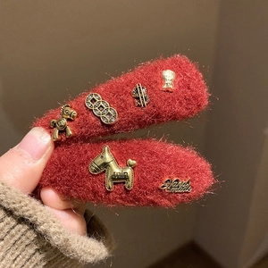 Macro view of red plush pony hair clips with gold lucky charms and win engraving