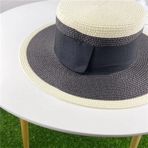 Detail of two-tone boater hat with black ribbon on a table in a garden setting