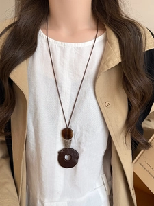 Detail of a vintage ethnic style pendant necklace with wood resin and tiger eye on a model