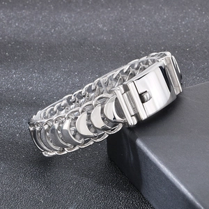 Macro shot of silver keel chain bracelet with polished square clasp on black textured surface
