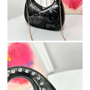 Detail of black marble acrylic clutch with rhinestone trim and heart handle design