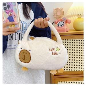 Detail of cute beige plush capybara handbag with embroidery held in a cozy room