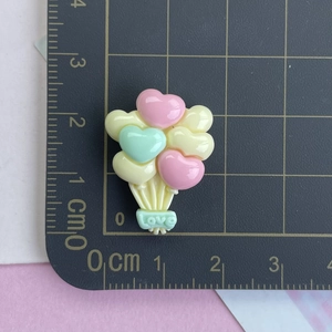 Détail du charm ballon coeur en résine colorée avec étiquette Love sur une règle