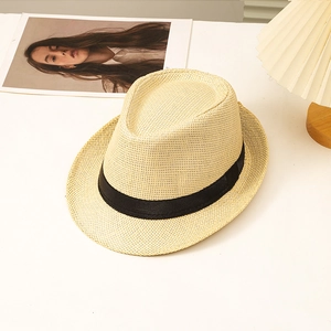 Close-up of beige straw fedora hat texture with black ribbon on a minimalist desk
