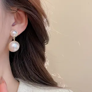 Detail of double pearl earrings with gold-plated metal trim on model showing texture