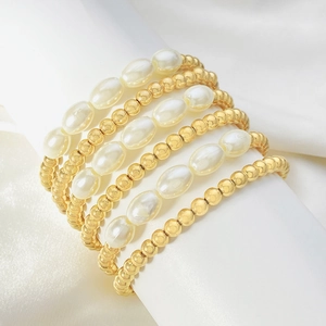 Dettaglio macro di un bracciale multistrato con perle bianche e sfere dorate su seta