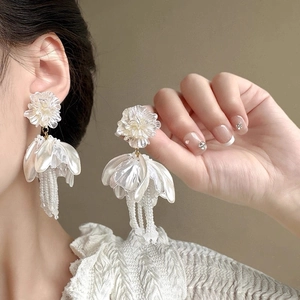 Detail of flower stud earrings with elegant imitation pearl tassels on a fashion model