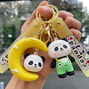 Close-up of cute cartoon panda keychain set with yellow moon and green overall doll