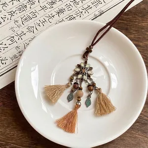 Détail du pendentif fleur rétro avec perles en bois et pompon sur un livre vintage