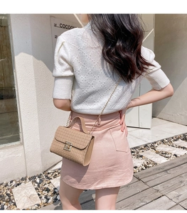Detail of beige textured crossbody bag with gold chain strap and metal handle
