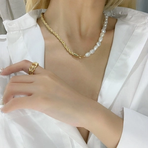 Close-up of asymmetric necklace with baroque pearls and golden twisted metal chain