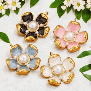 Floral enamel pendants with pearls in pink, black, blue and white on marble surface
