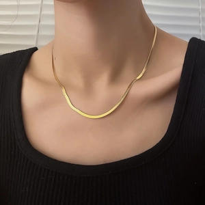 Close-up of a layered golden snake bone necklace showing flat metallic fish-scale texture