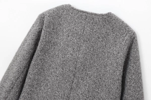 Gros plan sur la texture bouclée grise et les détails du col d'une veste courte chic