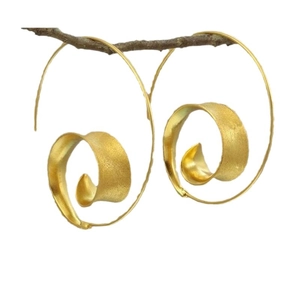 Boucles d'oreilles spirales dorées à texture mate suspendues à une branche