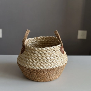 Two-tone woven straw storage basket with jute handles and decorative leather patch