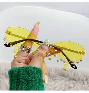 Gros plan de lunettes de soleil sans monture jaunes en forme de larmes avec strass et branches dorées