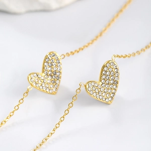 Macro shot of gold plated heart pendants with pavé set crystals on a fine chain