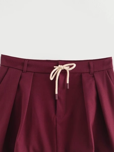Detail of burgundy waist with white drawstring cord and pleated fabric texture