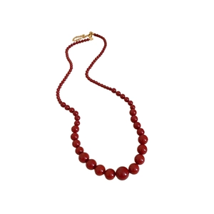 Collier de perles rouges dégradées avec fermoir doré sur fond blanc épuré