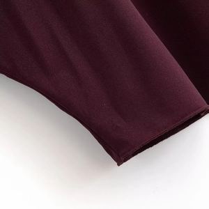 Close-up of deep purple knit top showing high-quality stitching and fabric texture