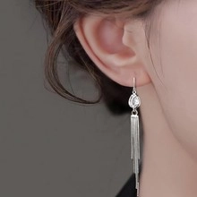 Dettaglio macro di eleganti orecchini a nappa in argento con catenine e zirconi cubici