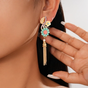 Détail de boucles d'oreilles fleuries à pompons, fleurs rose corail et perles