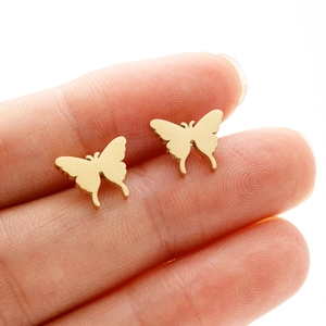 Polished gold butterfly stud earrings in stainless steel on fingertip for scale
