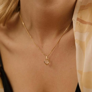 Close-up of a sparkling heart pendant necklace in gold finish worn by a female model
