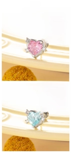 Detail view of heart-shaped zircon earrings in pink and light blue on a ceramic tray