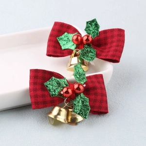 Detail of red plaid Christmas bows with gold bells and green leaves on white tray