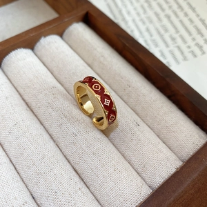 Close-up of a 14k gold-plated open ring with red enamel and floral pattern in a box