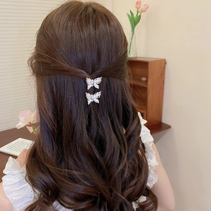 Close-up of white butterfly hair clips with pearls and diamonds worn on a half-up hairstyle