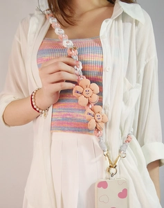 Close-up of hand-woven phone lanyard with pink daisy smile flowers and gold clasp