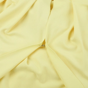 Détail du crochet métallique sur la robe en maille jaune montrant la texture du tissu