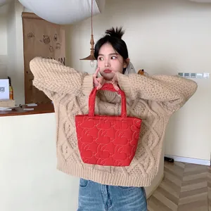 Detail of red quilted tote bag with rabbit pattern carried by model in casual style