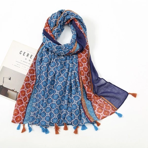 Detail of bohemian print scarf with colorful tassels and floral patterns on white background