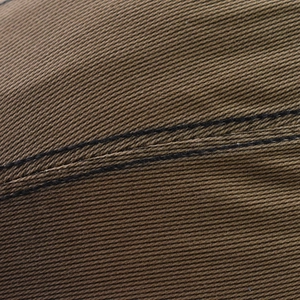 Detail of brown cotton twill fabric with black double stitching on a beret cap
