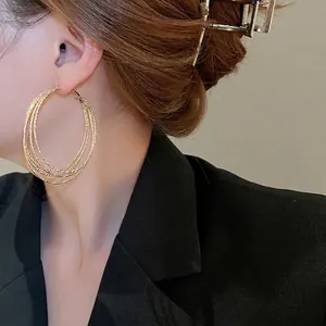 Fashionable layered gold circle hoop earrings with textured finish on female model