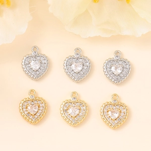 Gold and silver heart pendants with zircon inlay displayed on a soft floral background