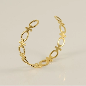 Detail of gold-plated cross hollow bangle featuring twisted oval link texture